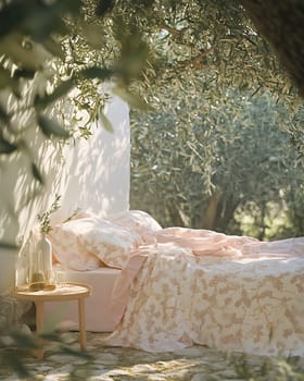 A serene outdoor bedroom features a floral patterned bed and rustic table, surrounded by lush olive trees on a sunny day.