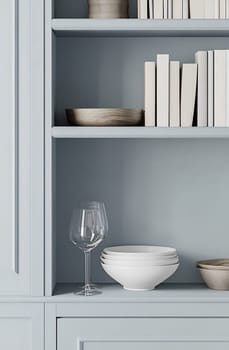 A soft blue kitchen shelf holds white bowls, a wine glass, and stacked books, creating a serene and organized atmosphere.