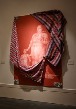 Venice, Italy - May 7 2024: 60th Art Biennale in Venice. Miscegenation Masks VII, Moxa Nation Woman and Infant. Red iron oxide, press clippings,  imitation gold leaf and cotton Andean Fabric on canvas