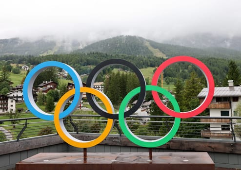 The Olympic rings in Cortina d Ampezzo against the background of the cloud-covered Dolomites. Italy