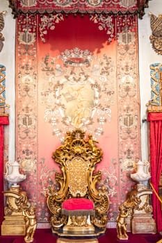 Isola Bella, Italy - 1 August 2023: antique throne in gold and red velvet. Old royal chair, luxury vintage.