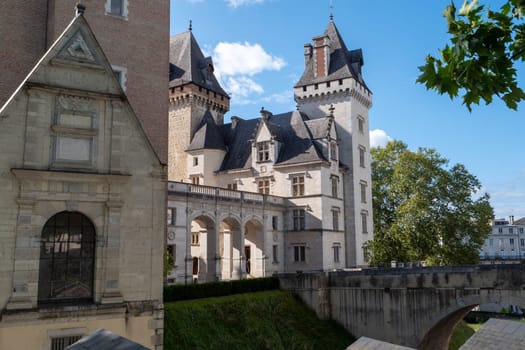 A large building with a tower and a small building in the background. The large building has a lot of windows and a balcony, Pau, France