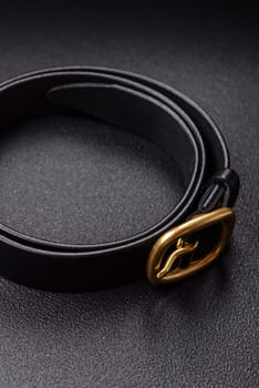 New leather women's belt with an old-style metal buckle on a dark concrete background