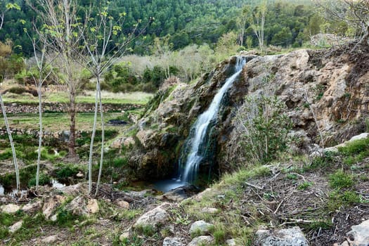 Small waterfalls in a mountain stream on a sunny day.long exposure. Mystic, vegetation, stone walls, lonely, empty space, romantic, idyllic.