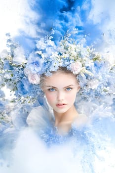 Face of spring. Young woman with striking blue eyes and delicate features wears a stunning headdress made of spring flowers.