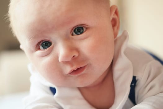 Four months old baby boy crawling on bed, detail on his head and face expression