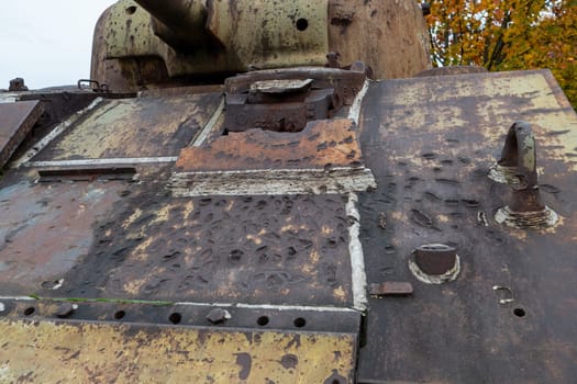 The tank is old and rusty, with a lot of damage. The front of the tank has a hole in it, and the rest of the tank is covered in rust. The tank appears to have been in battle