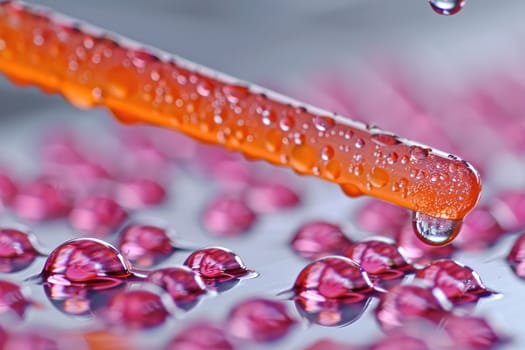A Single Orange Droplet About to Join a Pool of Pink Droplets