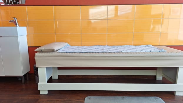 Minimalist spa treatment room with orange tile and massage table.