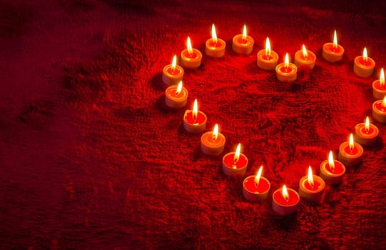 Heart-shaped candles arrangement on red background. Romantic and warm. Perfect for Valentine's Day.