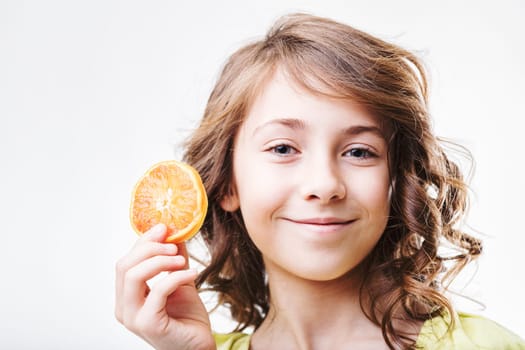 Cheerful young girl holding a vibrant slice of orange, embodying the joy of healthy eating and nutrition for children. Celebrating freshness and wellness through nutritious choices