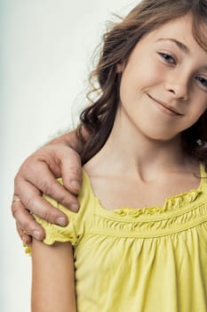 Portrait capturing a smiling girl enjoying the warmth of her father's hand resting gently on her shoulder, embodying comfort, support, and a strong family bond