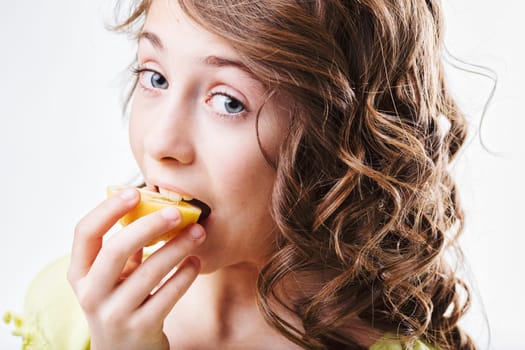 Curly-haired girl biting into a juicy lemon slice, making a hilarious face in response to the intense sourness, capturing the playful essence of childhood and healthy eating