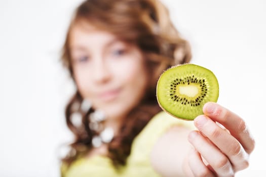 Young girl holding up a slice of fresh kiwi fruit, celebrating healthy eating habits and fostering a passion for natural foods packed with vitamins and antioxidants