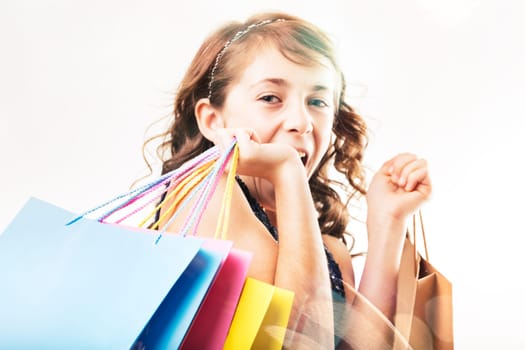 Excited young girl is holding colorful shopping bags and showing her happiness after a successful shopping spree, isolated on a white background
