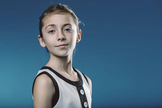 Young girl exuding confidence against a blue background, showcasing poise and maturity, capturing the essence of youth and limitless potential