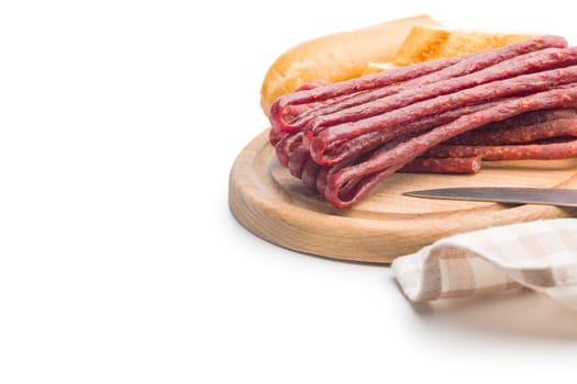 Smoked kabanos. Mini dried thin sausages on a cutting board isolated on white background