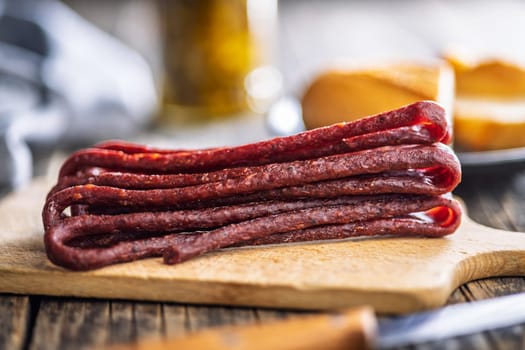 Smoked kabanos. Mini dried thin sausages on cutting board on a wooden table.