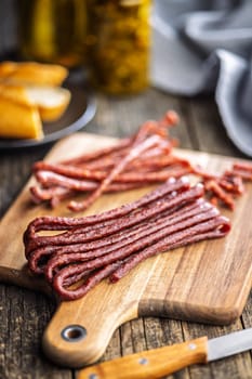 Smoked kabanos. Mini dried thin sausages on cutting board on a wooden table.