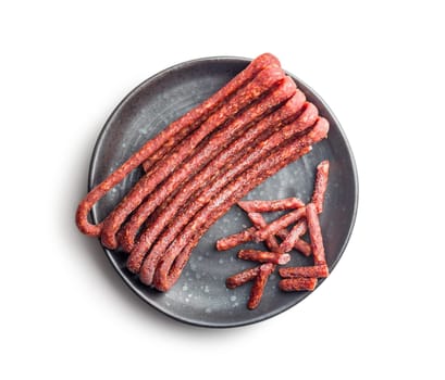 Smoked kabanos. Mini dried thin sausages on plate isolated on a white background
