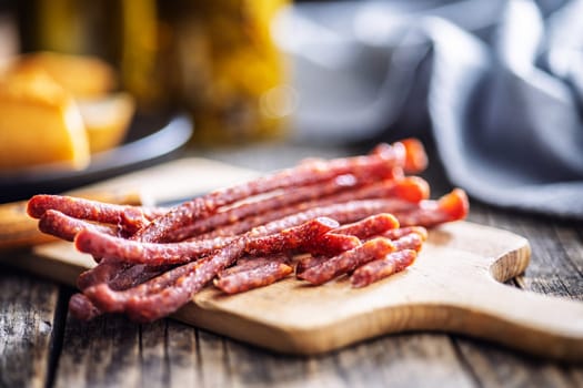 Smoked kabanos. Mini dried thin sausages on cutting board on a wooden table.
