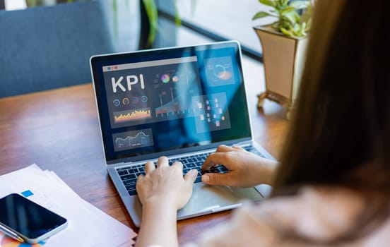 Businesswoman analyst utilizes a computer and a dashboard for business data analysis and a data management system with KPI. The concepts of technology, finance, operations, sales, and marketing.