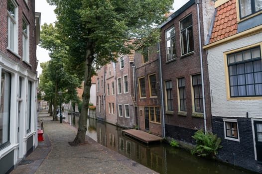 Houses on a water canal, a small street and with boats in the old town of Alkmaar in the Netherlands