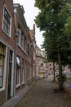 Houses on a water canal, a small street and with boats in the old town of Alkmaar in the Netherlands
