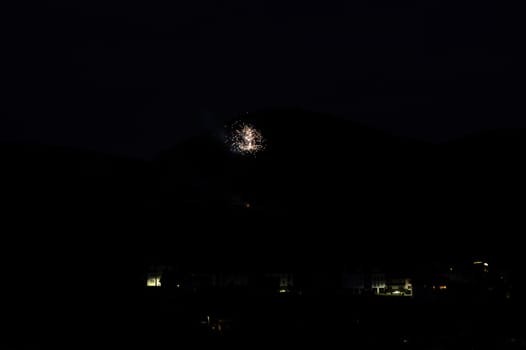 A firework rocket in the sky on a mountain at night, a few illuminated houses in the foreground,A firework rocket in the sky on a mountain at night, a few illuminated houses in the foreground