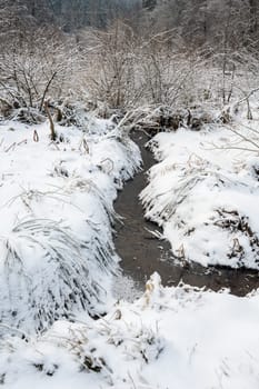 Small stream in the snow in wintertime
