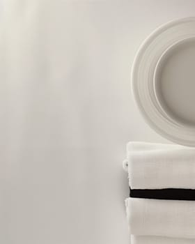 A simple, elegant arrangement of white ceramic plates and bowls set against a plain, off-white background, creating a serene and calming visual composition