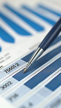 A close-up view of a ballpoint pen resting on financial paperwork with blue and white striped patterns in the background.
