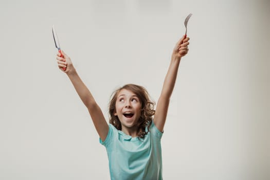 Cheerful girl holding cutlery, expressing excitement for mealtime with raised arms and a broad smile. Joy radiates from her as she anticipates the delicious food ahead