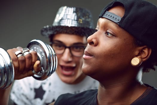 Two young men enjoying their workout together, one lifting a dumbbell while the other enthusiastically cheering him on, embodying friendship and motivation in their fitness journey
