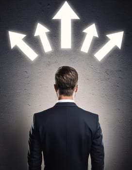 Rear view puzzled businessman facing a wall with multiple illuminated arrows pointing up. Decision-making or choosing the relevant path in career