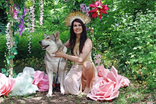 Fantasy photo of a woman dressed as a fairy with a wolfhound in a fairytale forest