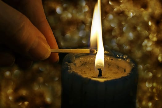 A woman lights a candle with a match in front of a glittering background