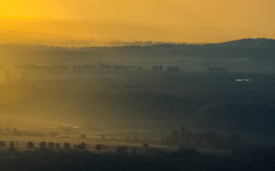Dawn in the mountains of Crimea. A light haze of mist over the mountains and rays of the sun through the clouds.