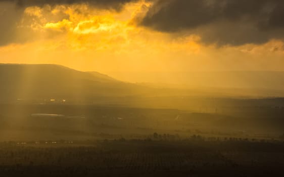 Dawn in the mountains of Crimea. A light haze of mist over the mountains and rays of the sun through the clouds.