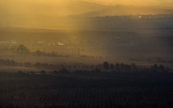 Dawn in the mountains of Crimea. A light haze of mist over the mountains and rays of the sun through the clouds.