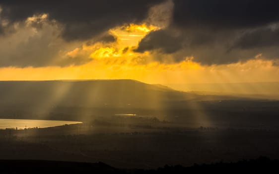 Dawn in the mountains of Crimea. A light haze of mist over the mountains and rays of the sun through the clouds.