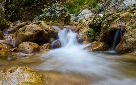Mountain small river in the forest with rapids and waterfalls. A forest creek.
