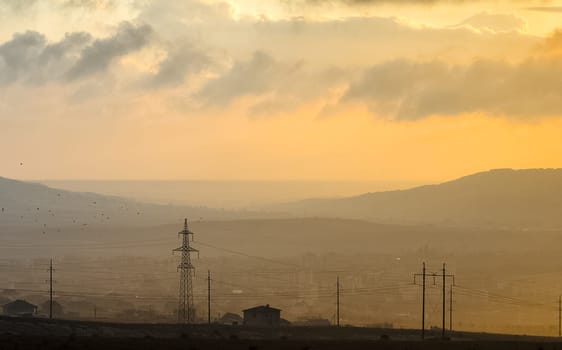 Dawn in the mountains of Crimea. A light haze of mist over the mountains and rays of the sun through the clouds.