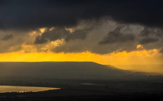 Dawn in the mountains of Crimea. A light haze of mist over the mountains and rays of the sun through the clouds.