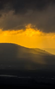 Dawn in the mountains of Crimea. A light haze of mist over the mountains and rays of the sun through the clouds.