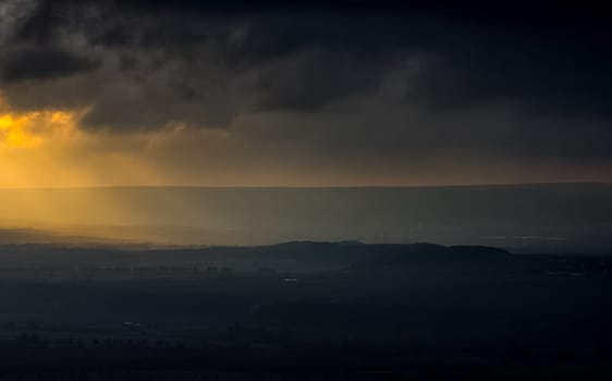 Dawn in the mountains of Crimea. A light haze of mist over the mountains and rays of the sun through the clouds.