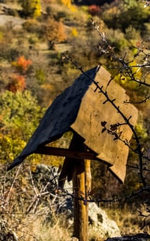 A wooden bird feeder with a roof.