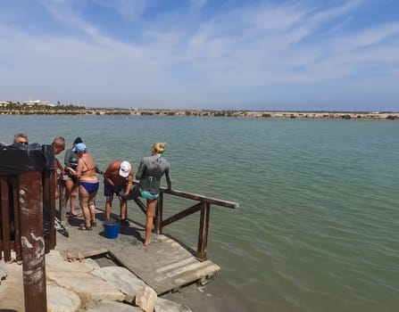 Alicante, Spain - July 24, 2019: People are wiped with mud. Mud baths in Spain.