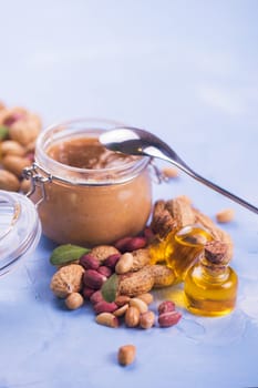 Natural peanut butter with oil in a glass jar and peanuts