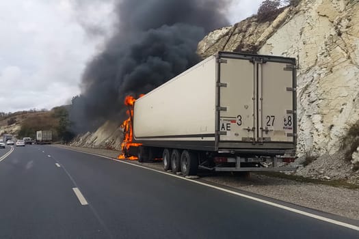 Burning truck on the road. The cab of the truck is on fire.